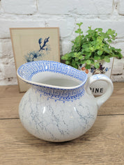 Broc joufflu en faïence blanche à effets marbrés et motifs géométriques bleus, style Art déco, signé de la manufacture Lunéville,