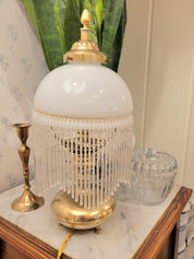 Superbe lampe, pied en laiton reposant sur 3 petits pieds en forme de pattes, abat-jour en opaline blanche et pampilles transparentes